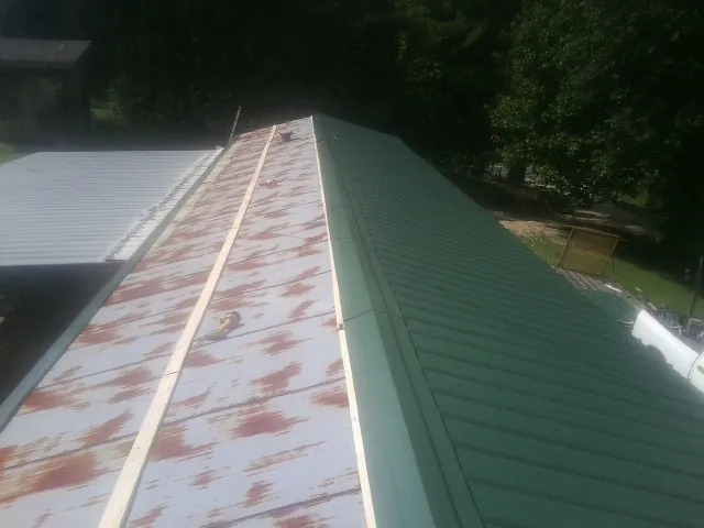 Old rusted panels beside newly installed green metal roofing — Wind Damage Roof Repair by Roofing Brothers in South Royalton