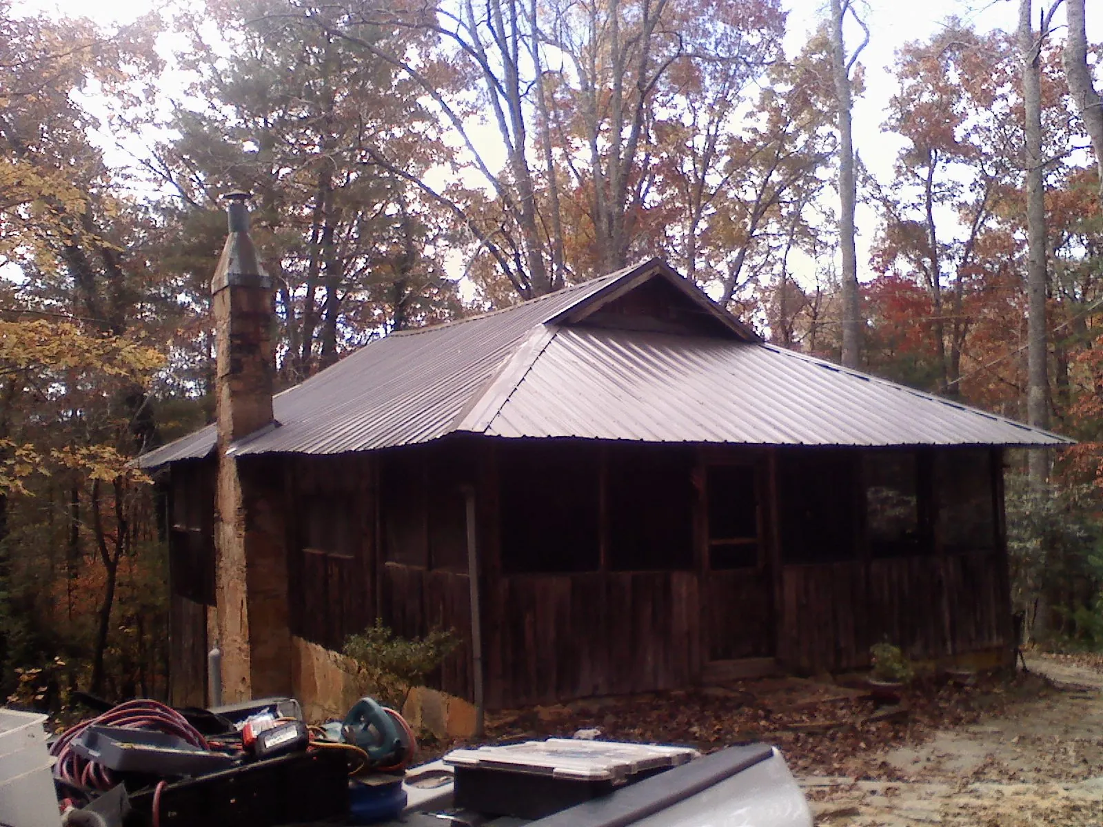 Brown metal hip roof on an old cabin with a stone chimney in South Royalton