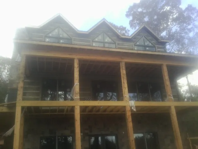 Dormers and porch framing on a large log home under construction — Roof Coating work by our crew in South Royalton