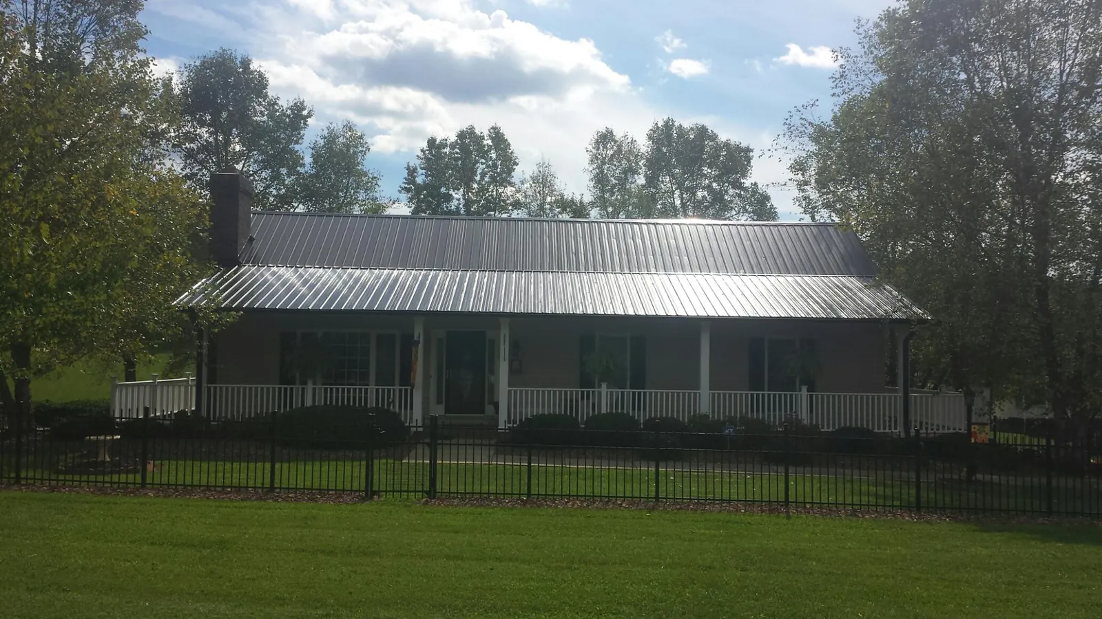 Gray metal roof on a brick ranch with a full width front porch — Gutter Guard Installation work by our crew in South Royalton