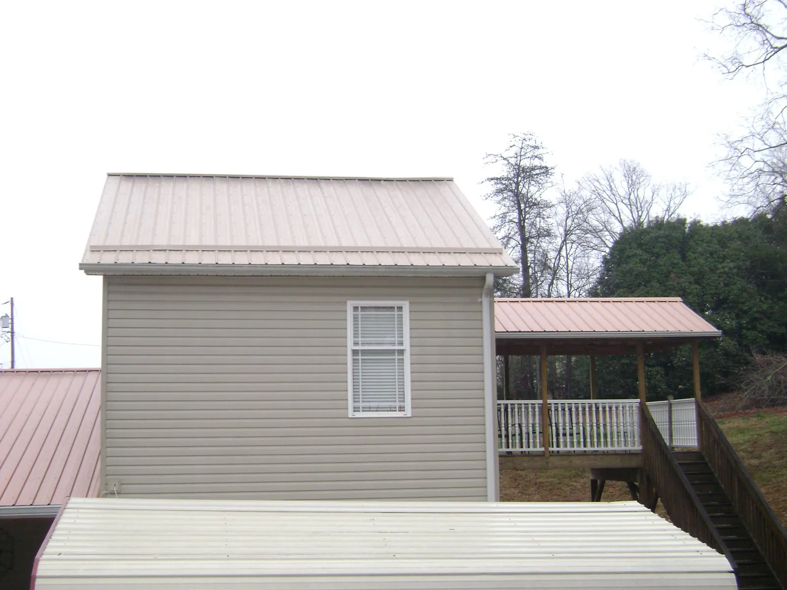 Tan metal roofs on a two story addition and attached porch, from a Roof Replacement job in South Royalton