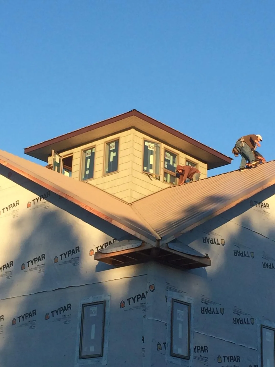 Roofers working around a rooftop cupola on a new metal roof at sunset — Roof Waterproofing in South Royalton by Roofing Brothers